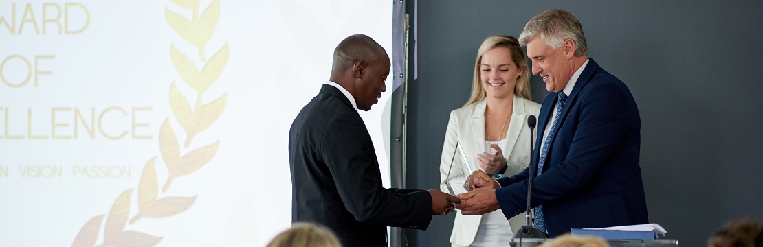 Man accepts an award onstage at a ceremony in front of a crowd.