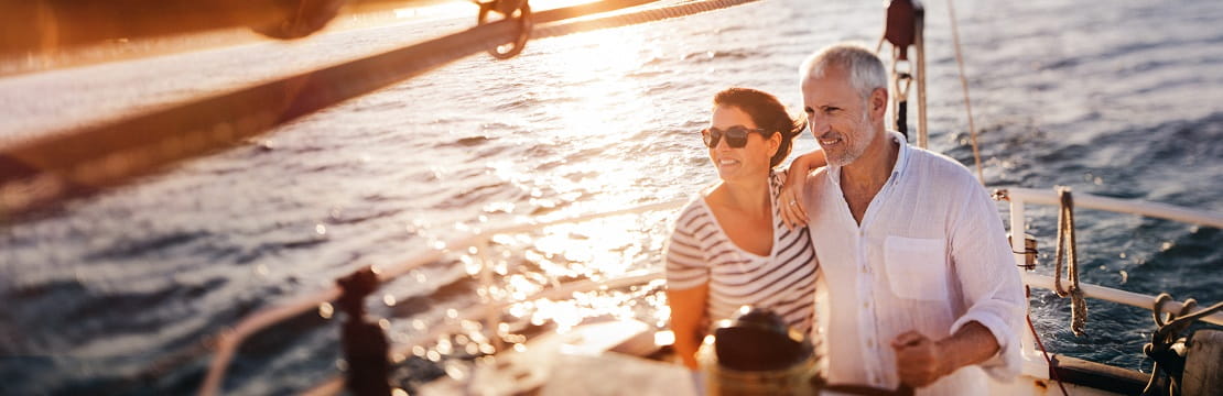 Couple cruises on a yacht at sunset.